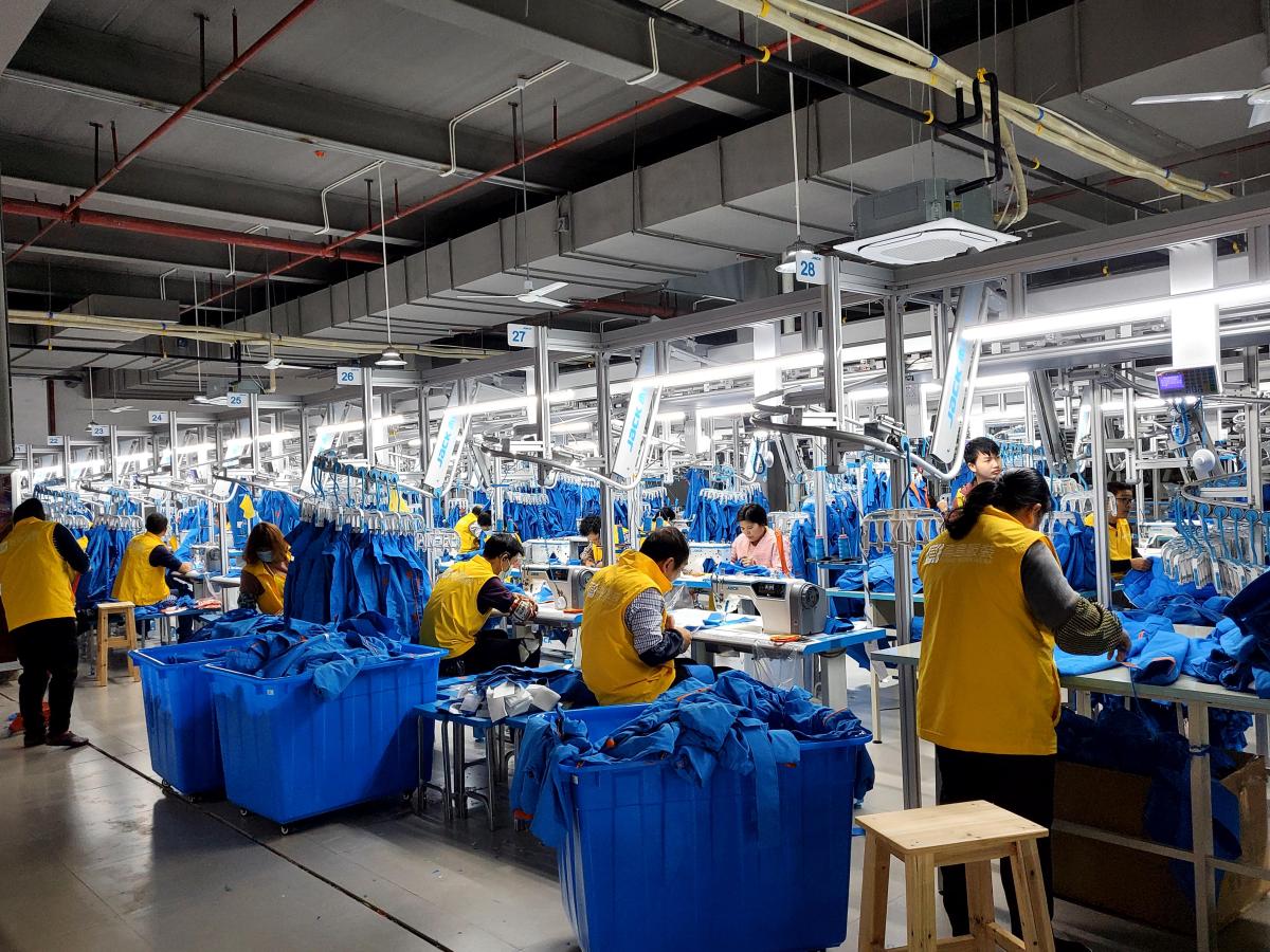 Active Pertemba garment sewing line with operators working on blue and yellow apparel
