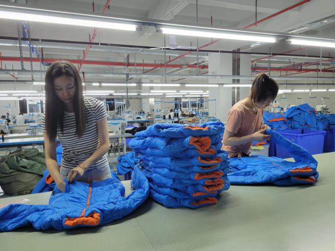 Workers sorting and arranging blue finished garments on a production table
