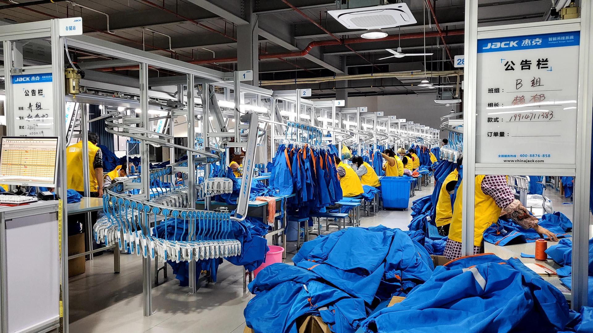 Wide garment production line with finished apparel and operators working across the inspection and assembly area