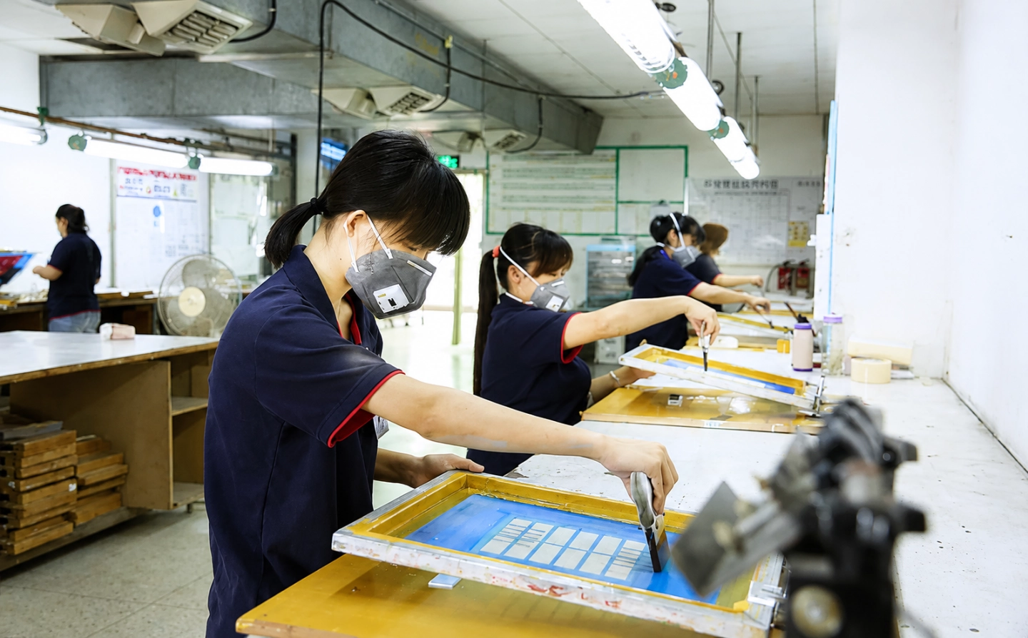 HileDisplay factory workers performing precision UV screen printing on cosmetic display stand components